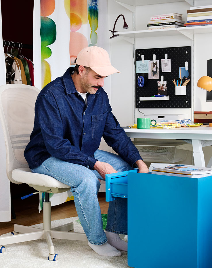 An office space features a beige FLINTAN office chair with a comfortable design near a desk and shelves with stationery.