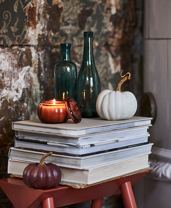 Seasonal styling on a side table with books, candles and pumpkins in soft tones, perfect for creating a warm and welcoming atmosphere.