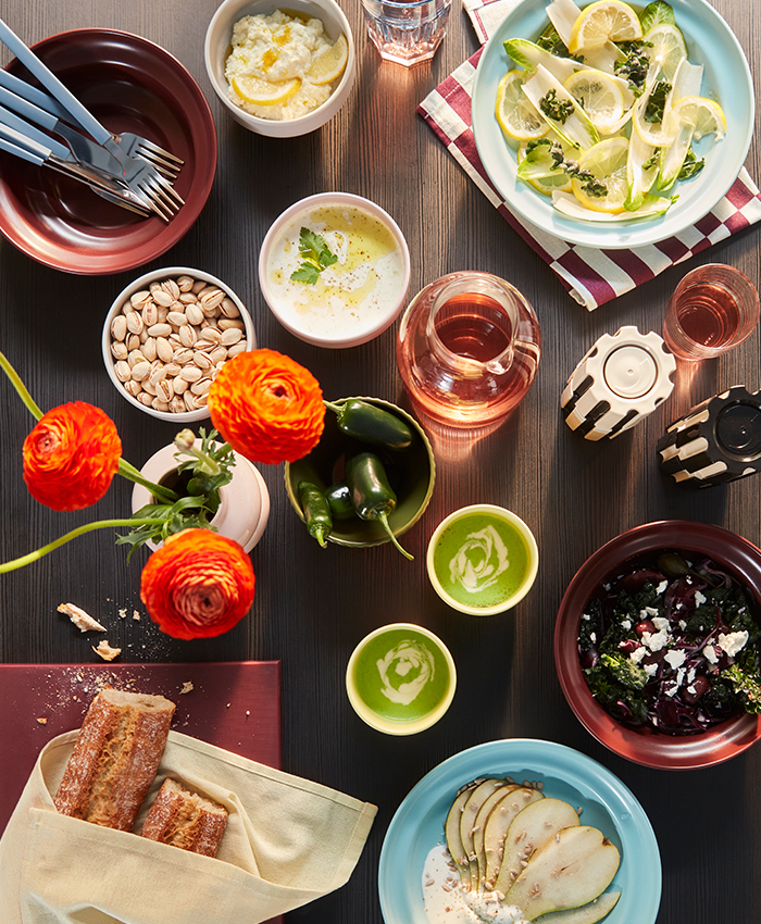 Table setting with food, drinks, and colorful tableware from the SPJUTLILJA collection.