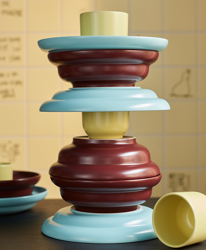 Decorative object from the SPJUTLILJA collection featuring stacked shapes in dark red, light blue, and soft yellow tones.