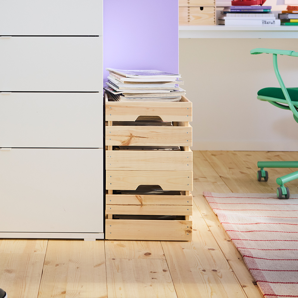 A room with a white VIHALS chest of 4 drawers, featuring a purple wall and wooden floor, beside natural wooden boxes.
