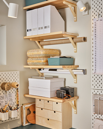 Wooden wall shelves organizing magazine files, storage boxes, paper rolls, and craft supplies.