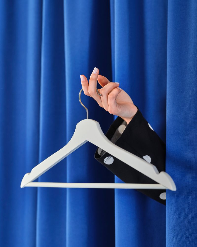 Rincón de armario elegante con cortinas GINSTMOTT y ganchos BUMERANG, creando un ambiente ordenado y moderno.