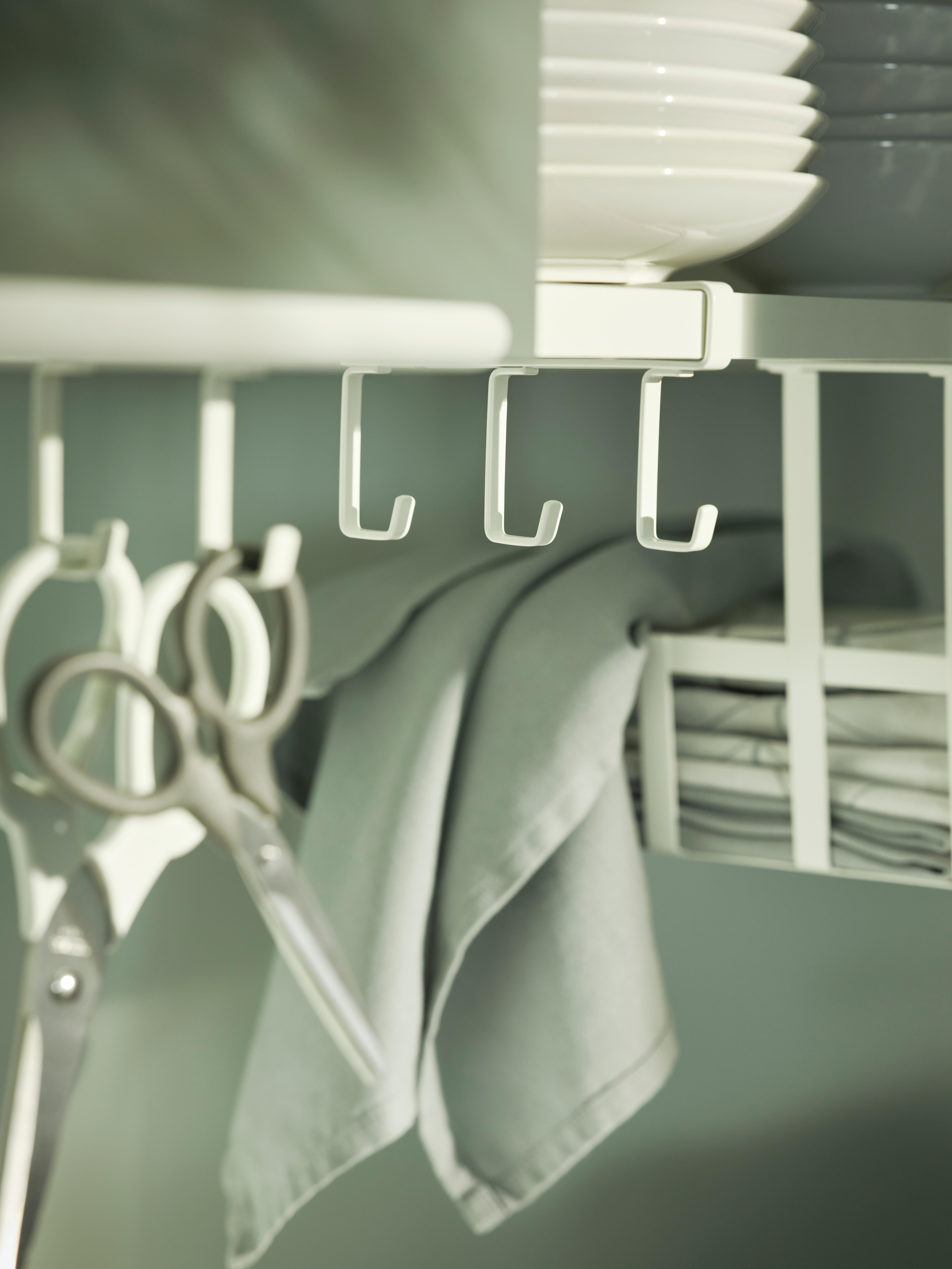 Kitchen organizer with hooks, scissors, and folded towels.