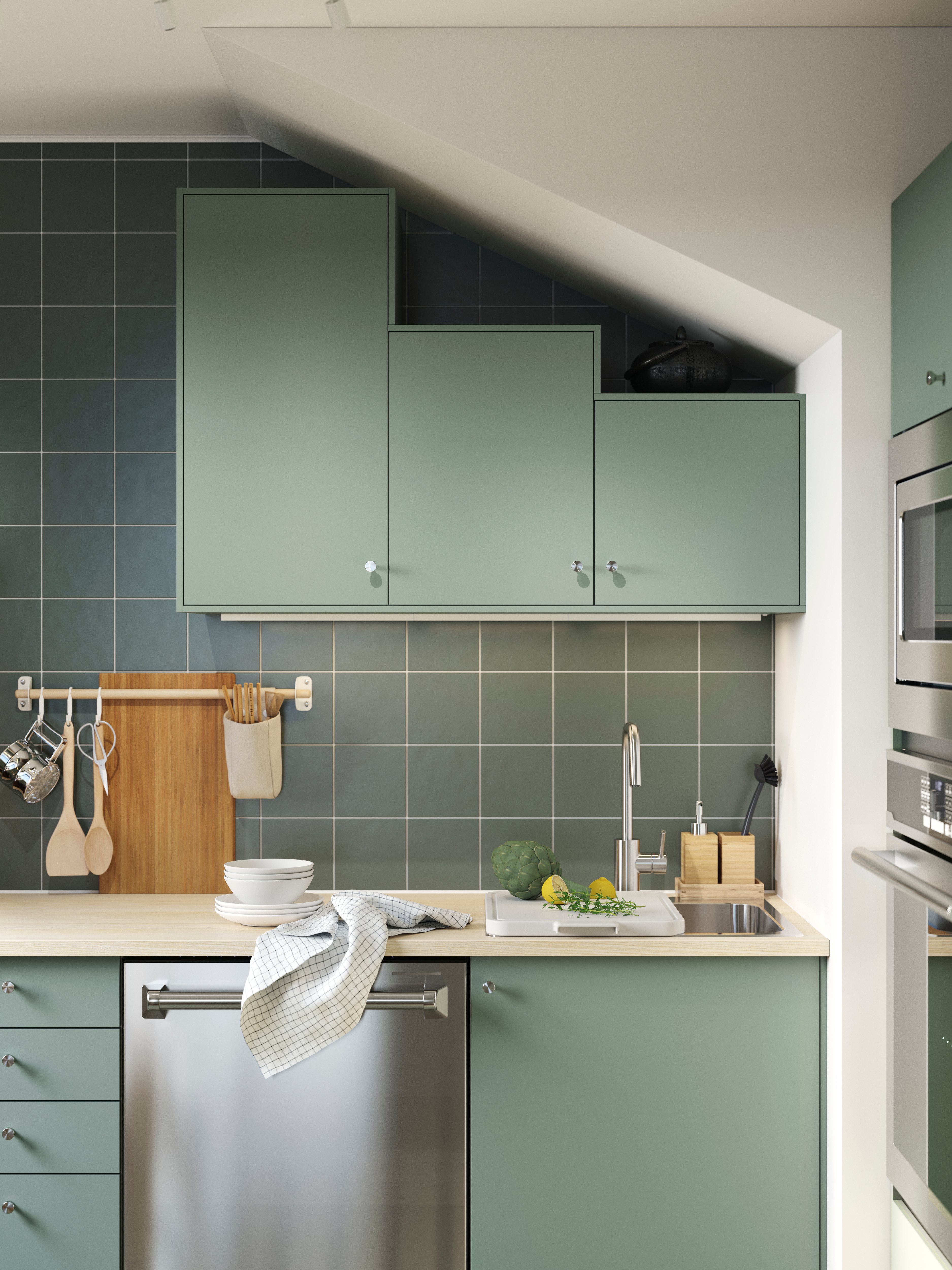 Modern kitchen with green cabinets, sink, and wooden countertop.