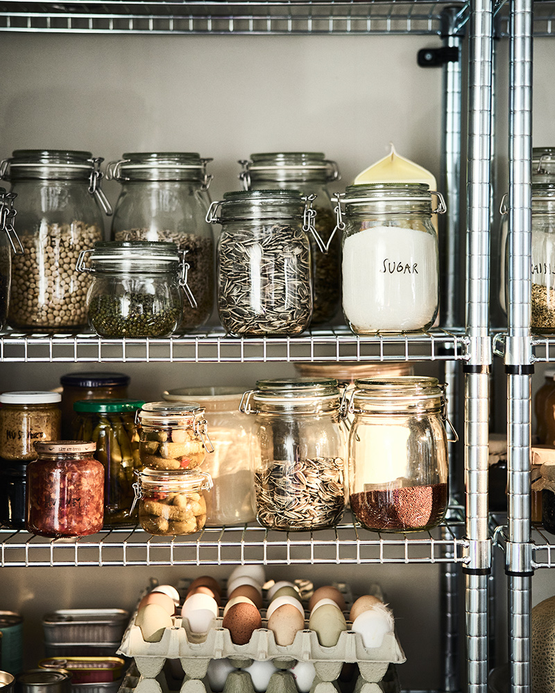 A metal shelving unit with various KORKEN food containers, bottles and jars on it.