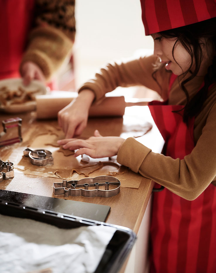A little girl arranging gingerbread cookies on VINTERFINT plates featuring various designs.