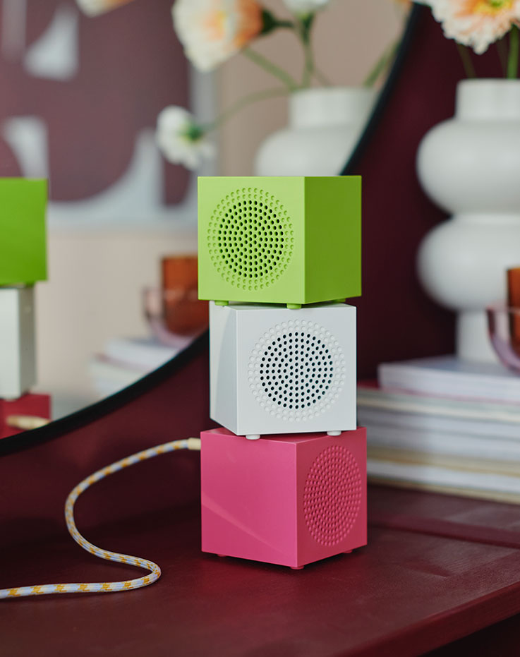 Three KALLSUP portable speakers in various eye-catching colors, stacked on top of one another.