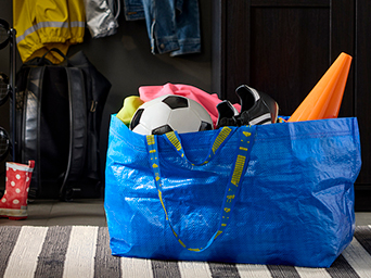 An IKEA FRAKTA bag filled with sports gear in the hallway of a house