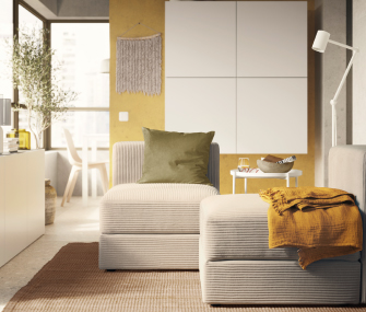 Beige modular armchair with olive green cushion and yellow blanket on a brown rug.