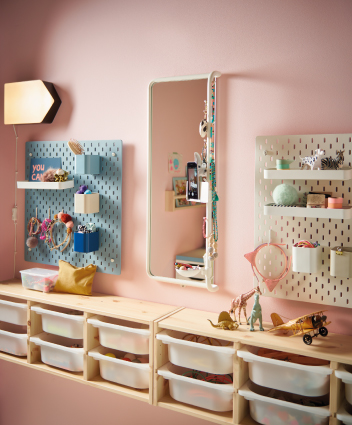 Rectangular mirror and pegboards for accessories mounted above a kids storage unit.