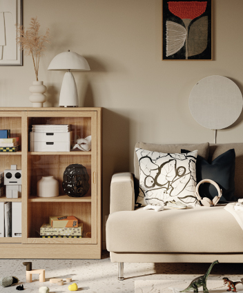 Beige sofa with a patterned cushion next to a light wood cabinet in a modern room.