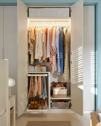 Open wardrobe with interior lighting, hung clothes, a pull-out shoe rack, and bins.