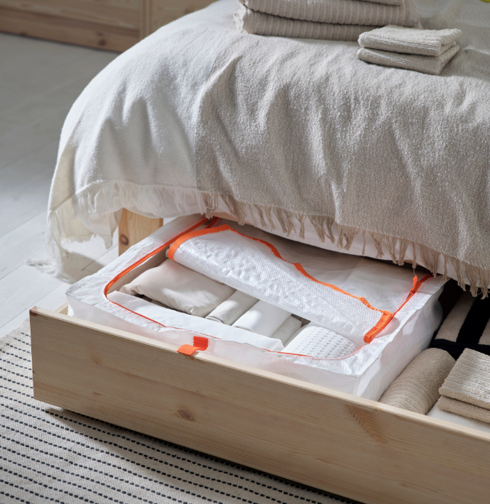 Zippered fabric storage bag with folded clothes inside an under-bed drawer.