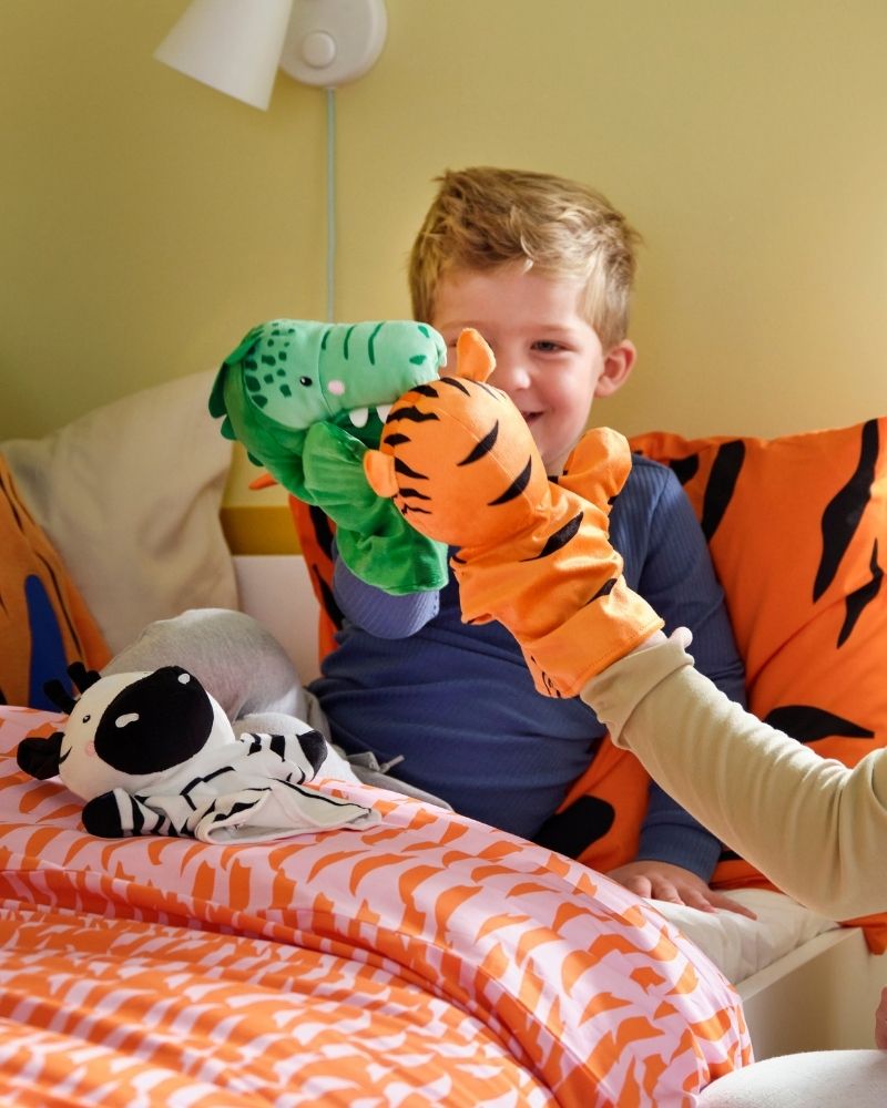 Un niño en la cama y una mujer están jugando con marionetas de mano NATTHÄGER.