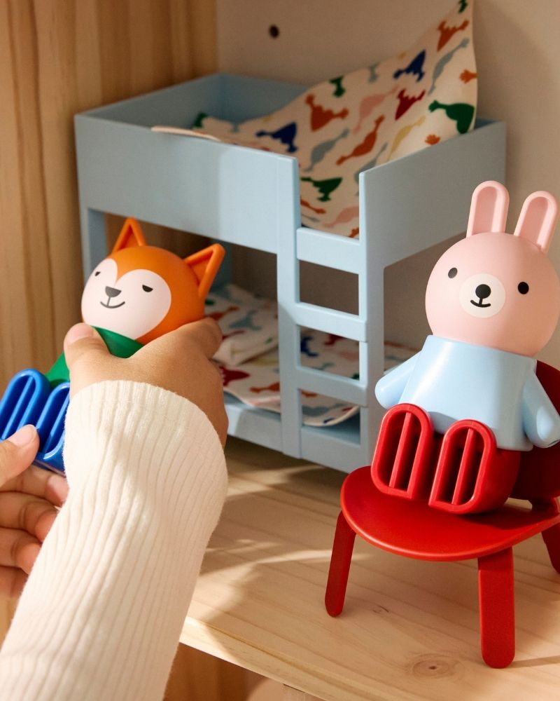 Un par de manos de un niño están jugando con las muñecas y la casa de muñecas HUSET.