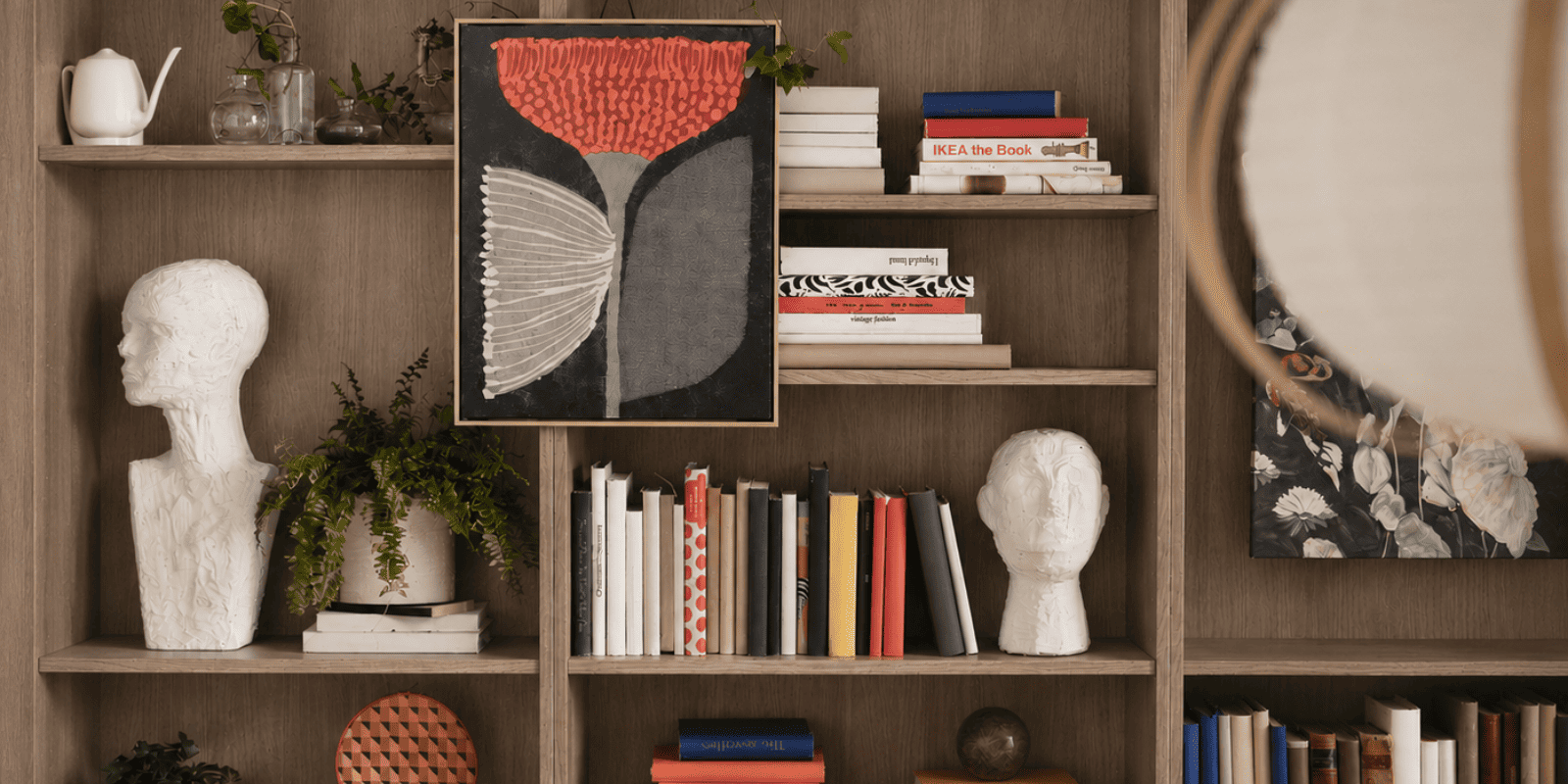 El salón cuenta con una estantería BILLY marrón con libros, objetos decorativos y plantas, lo que crea un espacio cálido y acogedor.