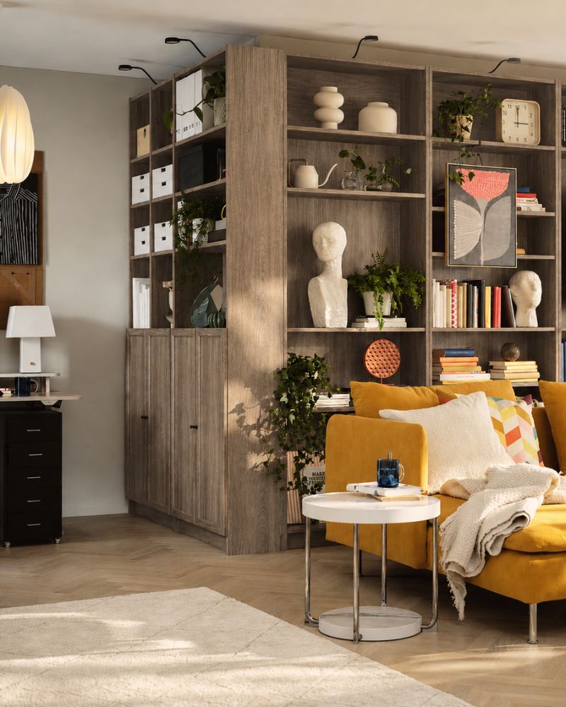 Un salón con una estantería BILLY marrón con efecto nogal, llena de libros y objetos decorativos.