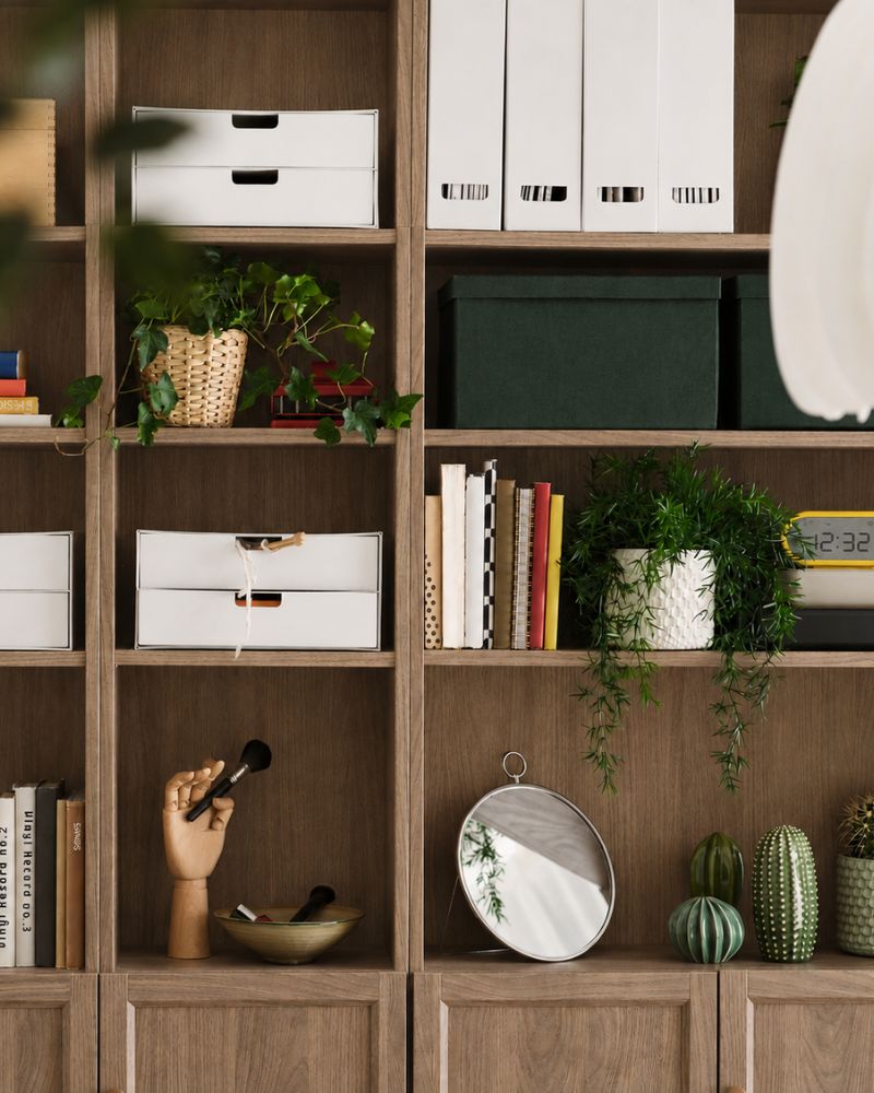 Un salón con una estantería BILLY marrón en la que se exponen libros y objetos decorativos, frente a una pared de madera.