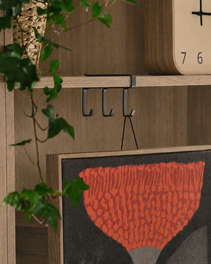 Un salón cuenta con un perchero de ganchos PÅLYCKE en color antracita fijado a la pared, rodeado de plantas decorativas.