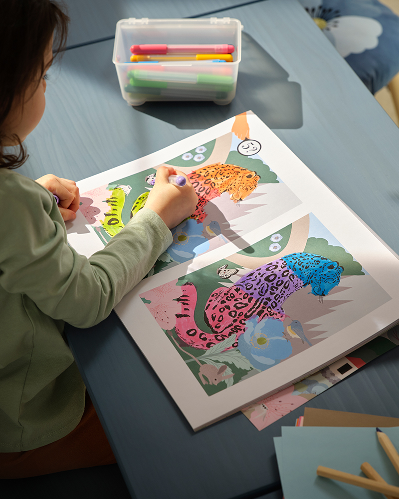 Un niño colorea un leopardo en el libro de actividades ALPTALL que tiene páginas para colorear y juegos.