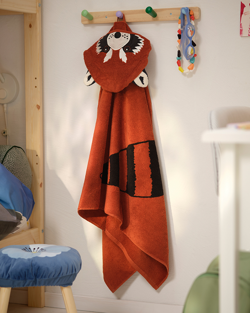 Una toalla de algodón ALPTALL de panda rojo cuelga de un gancho en una habitación infantil.