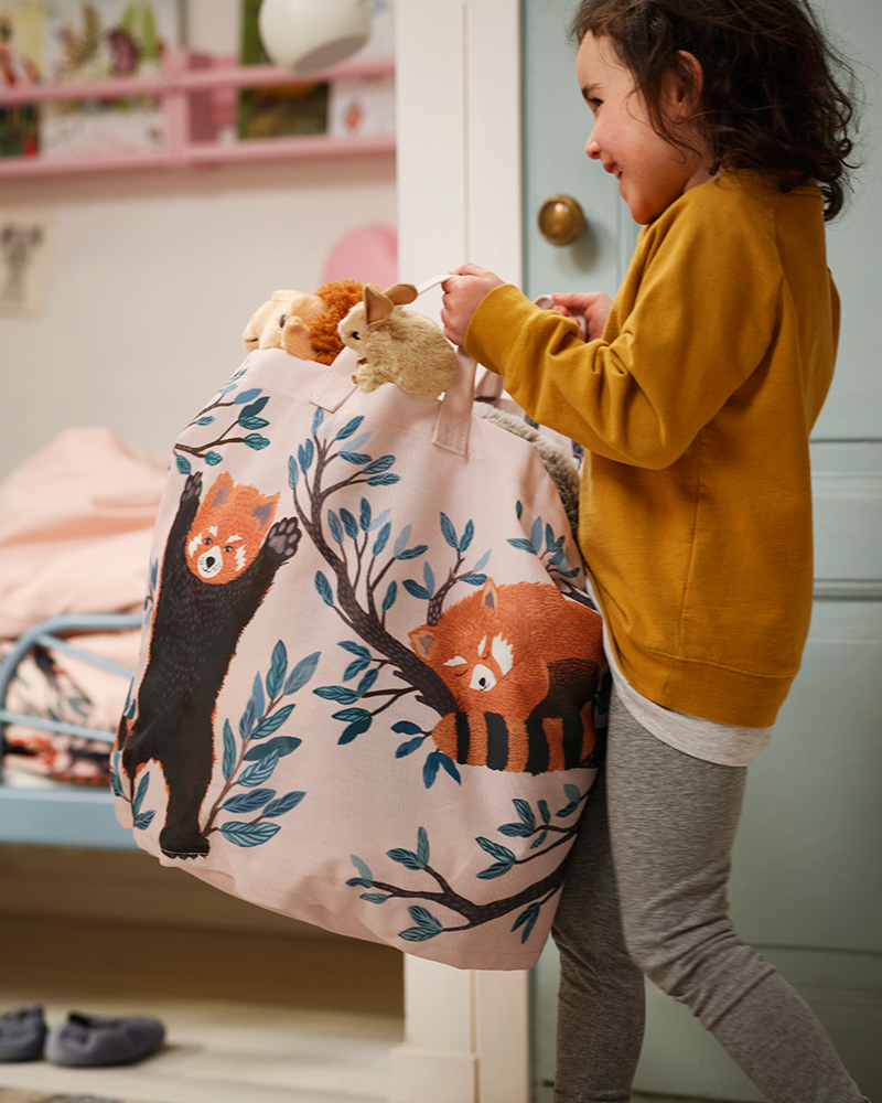 Un niño cargando una bolsa de almacenaje ALPTALL con un diseño de pandas rojos pintados a mano.