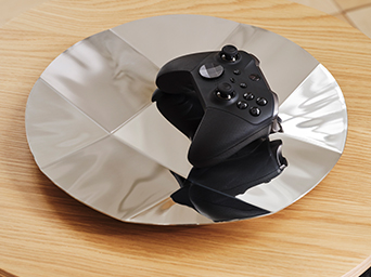 Close-up of an YXSTABY gaming D-pad controller platter holding a black XBOX controller.