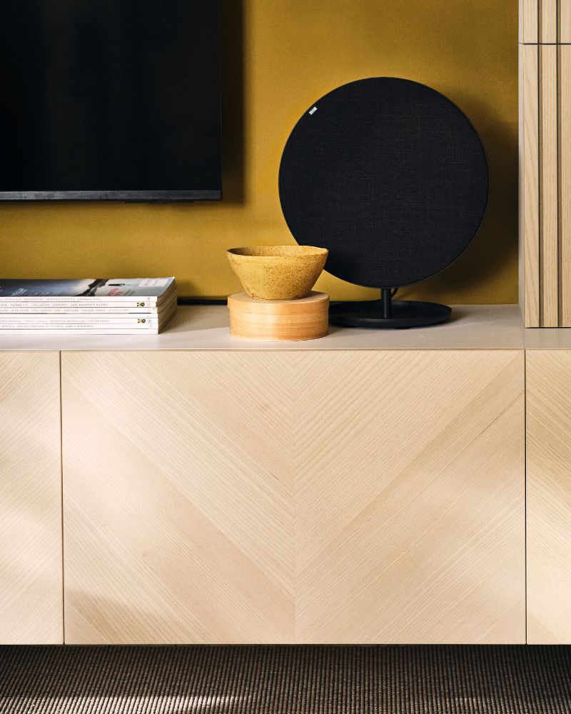 BESTÅ media storage combination with SOLSKYDD bluethooh speaker and bowls beneath a TV in a living room.