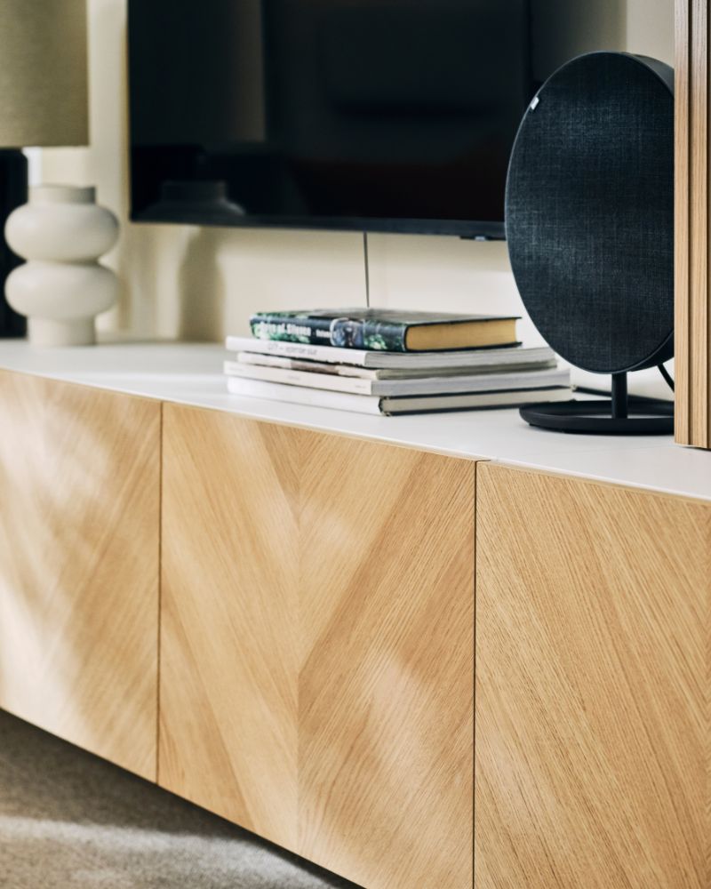 BESTÅ media storage combination with boks, decorative objects and a SOLSKYDD bluetooth speaker.