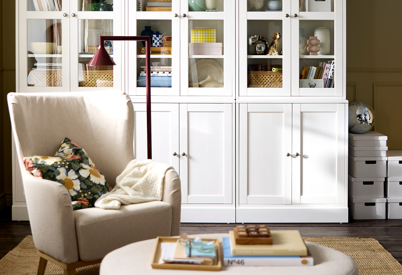 Una sala de estar que cuenta con una combinación de almacenamiento HAVSTA negra con puertas de cristal, donde se exhiben objetos decorativos y libros.