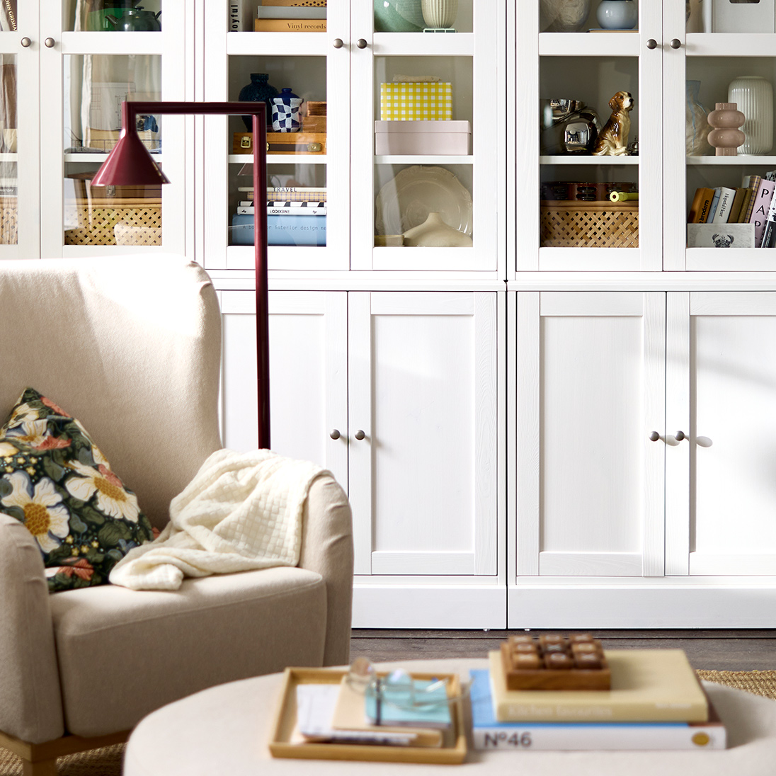 Una sala de estar que cuenta con una combinación de almacenamiento HAVSTA negra con puertas de cristal, donde se exhiben objetos decorativos y libros.