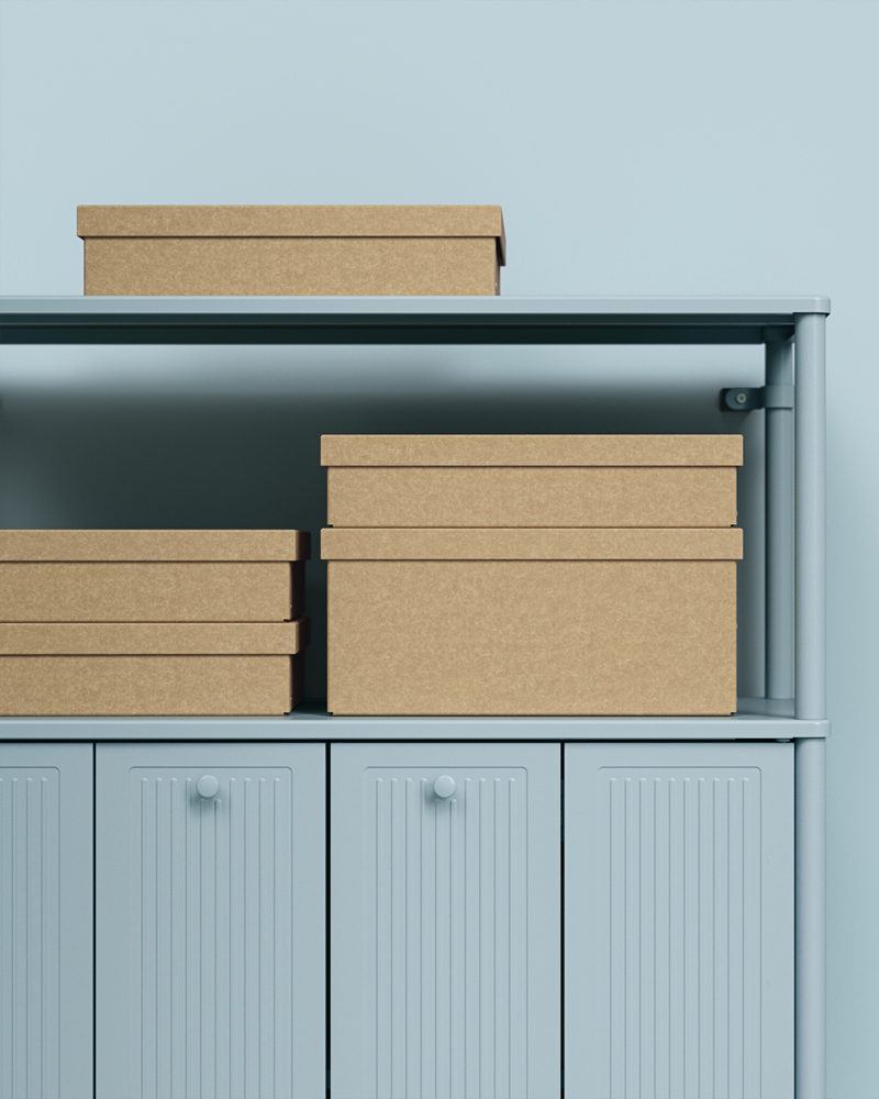 GÄRDESGÅRD storage boxes with lids stacked on the shelf of a light-grey-blue SÅGMÄSTARE cabinet against a light-blue wall.
