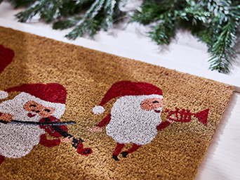 Regalos envueltos con papeles decorativos de motivos florales y cuadros en rojo, negro y blanco, colocados bajo un árbol de Navidad con luces cálidas y adornos festivos.