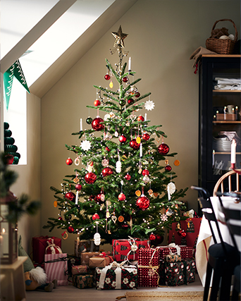 Peluches decorativos inspirados en personajes navideños colocados entre regalos envueltos en papel con motivos rojos y blancos junto a un árbol de Navidad.