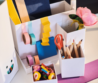 White desk organizer filled with pencils, scissors, tapes, and colorful school supplies.