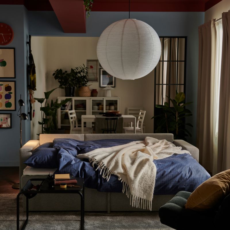 Cozy living room with BÅRSLÖV sofa bed, DYVLINGE swivel chair, STOENSE rug, OLSERÖD side table and SANELA curtains.