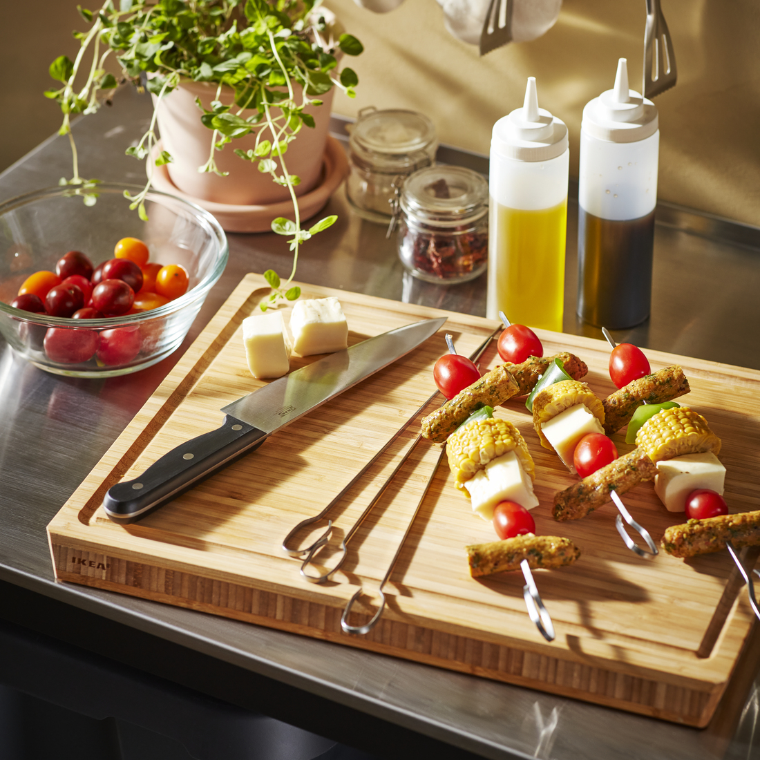A bamboo cutting board with a knife, cheese, and vegetable skewers.