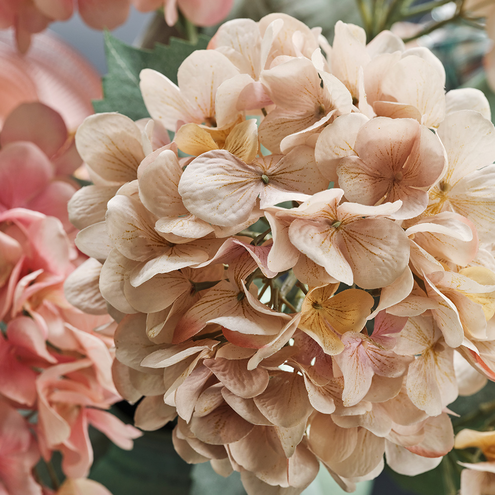Un primer plano de una flor artificial SMYCKA de color beige claro, inspirada en una hortensia, con sus numerosos y pequeños pétalos.
