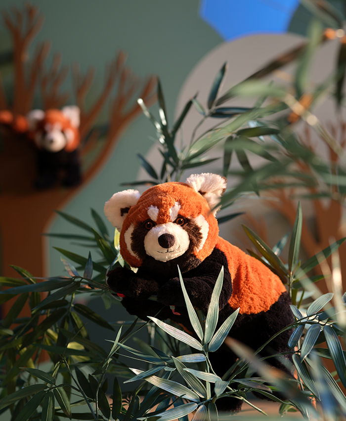 Un panda rojo de la colección ALPTALL de peluche subido en una rama 