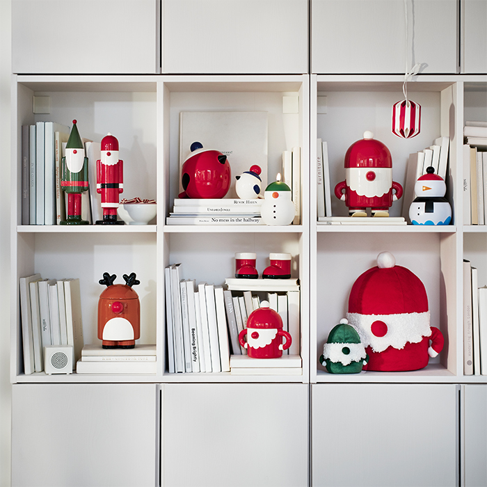 White shelving unit decorated with Christmas ornaments and figures in red, green and white, alongside books and Christmas soft toys.