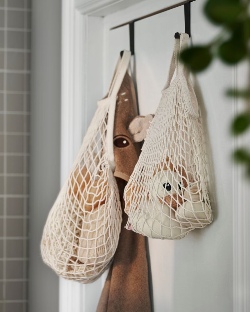 Almacenaje práctico para baño con bolsas de red KUNGSFORS y ganchos para puerta SKOGSVIKEN para organizar accesorios.