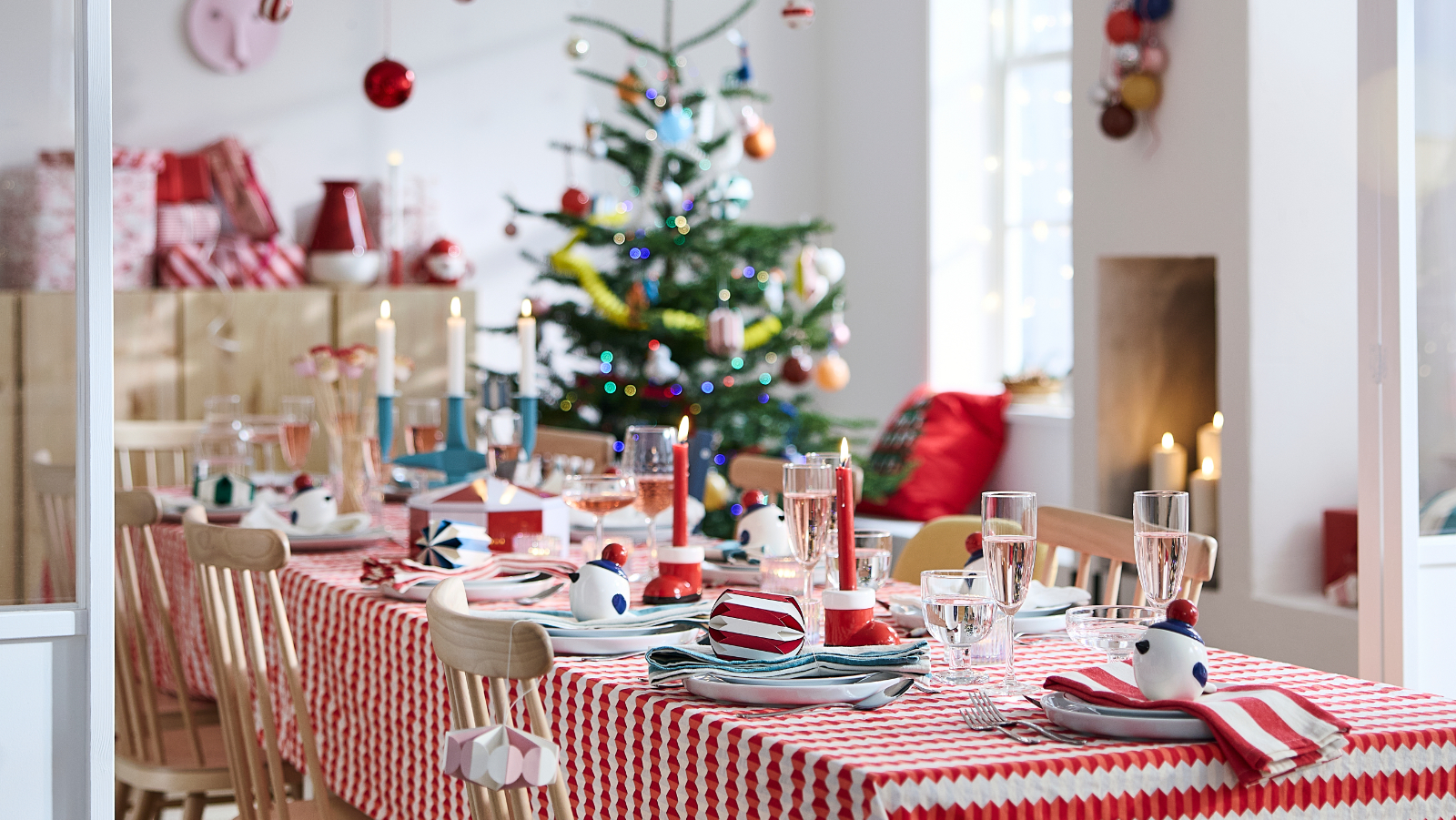 Festive Christmas dining table with red decor, candles, and decorated holiday tree
