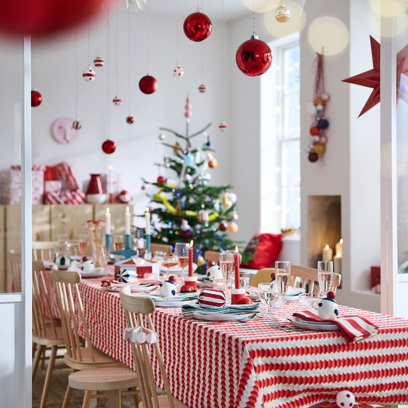 Festive Christmas dining table with red decor, candles, and decorated holiday tree