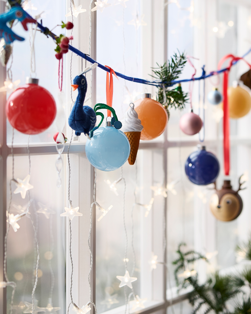 Colorful Christmas ornaments and star lights hanging in a bright festive window display