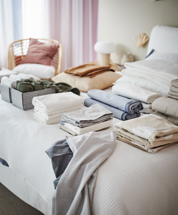 Folded bedding and linens neatly arranged on a bed.