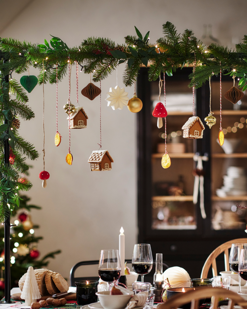 Christmas dining table decorated with hanging ornaments, evergreen garland, and candles