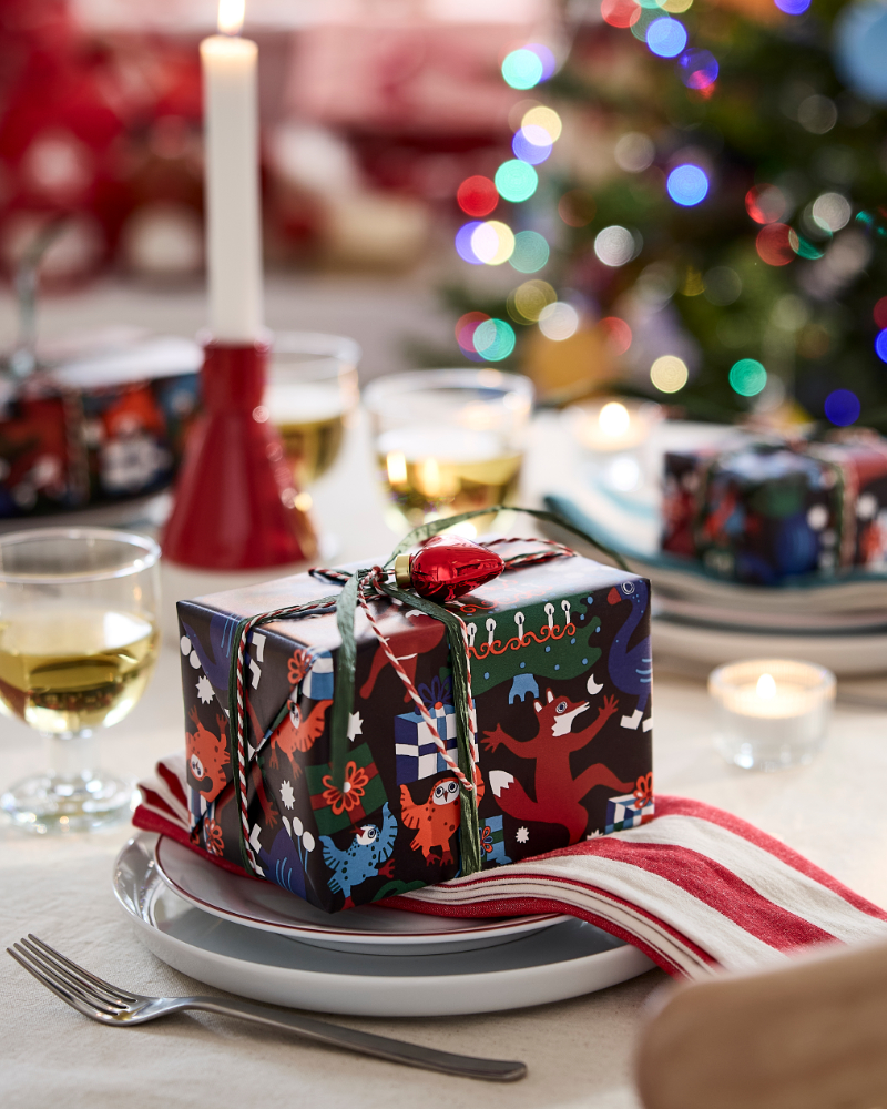 Christmas gift box wrapped in decorative paper on a holiday table with candlelight