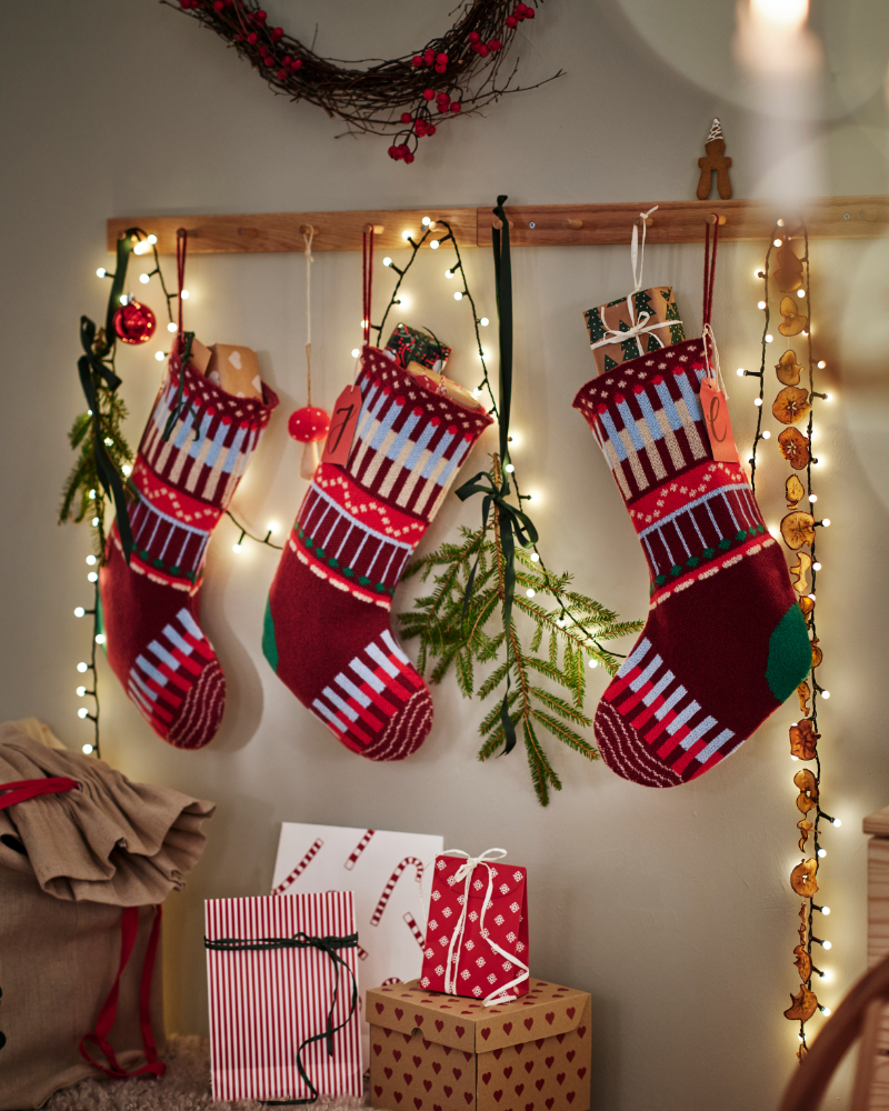 Red Christmas stockings with wrapped gifts, garland, and warm decorative lights