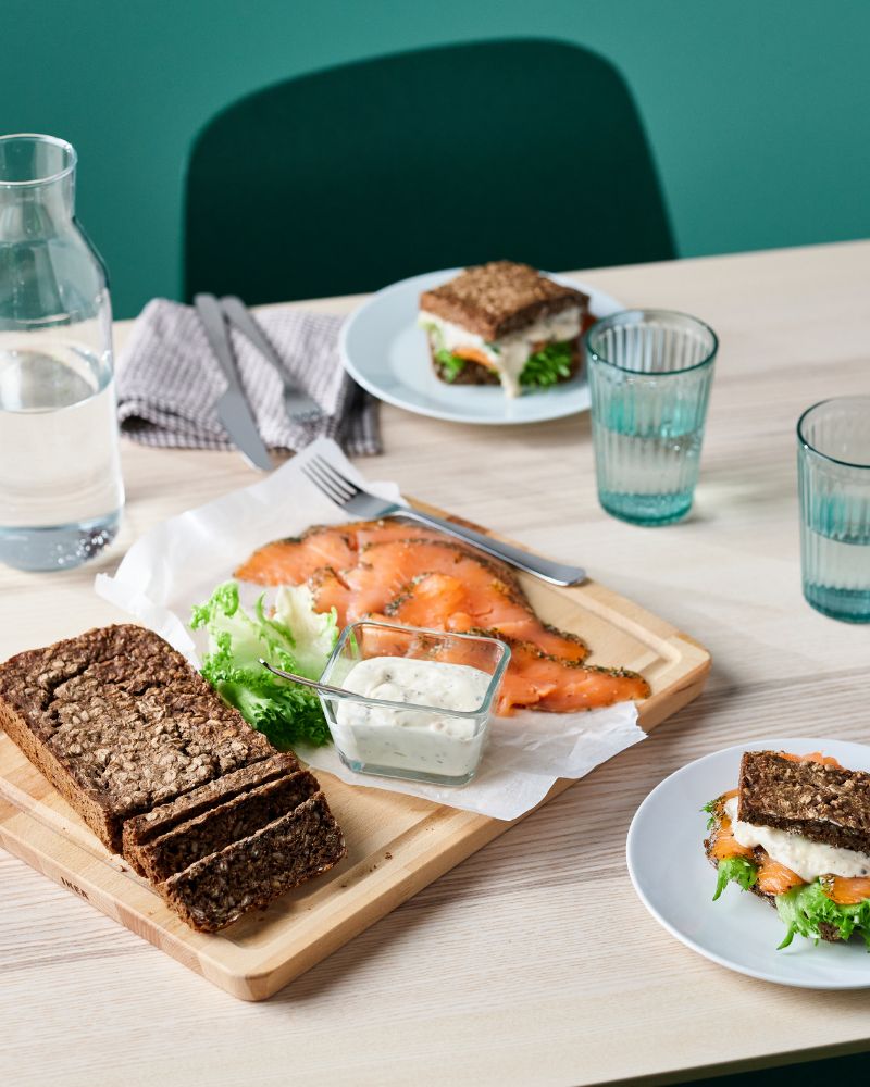 Inviting dining setting with SJÖRAPPORT cured salmon, HAVSTULPAN chopping board, GODMIDDAG plate and VARDAGEN glass.